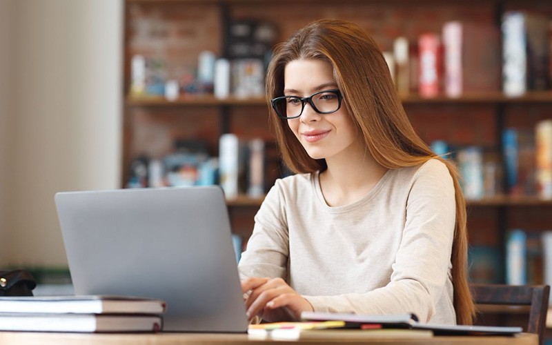 Enhance education. Woman with glasses working using a laptop