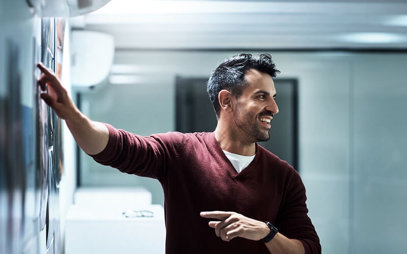 marketing-teammate-pointing-to-asset-on-wall marketing-teammate-pointing-to-asset-on-wall