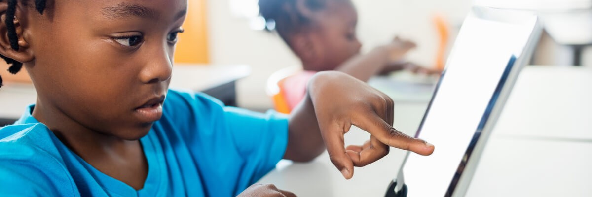 Student using tablet Young student using tablet in classroom