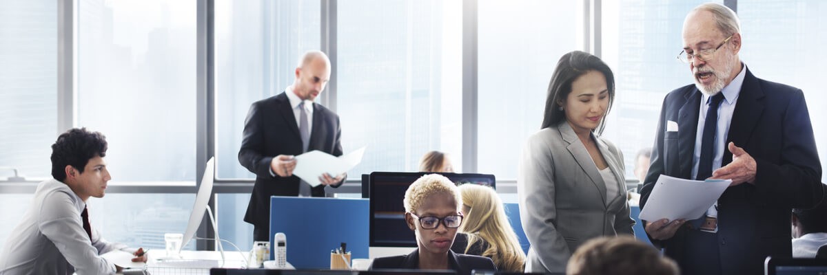 Agile for Federal Agencies: Challenges and Strategic Solutions IT professionals talking while looking at papers and devices