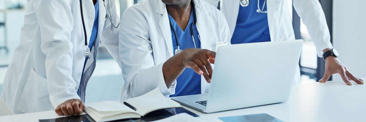 Drive down costs and minimize IT management while increasing patient satisfaction Healthcare professionals gathered around laptop