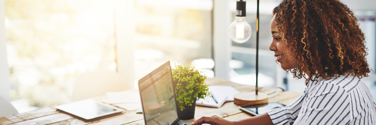 Four Trends Shaping the Future of Work Smiling woman works at desk with laptop remotely