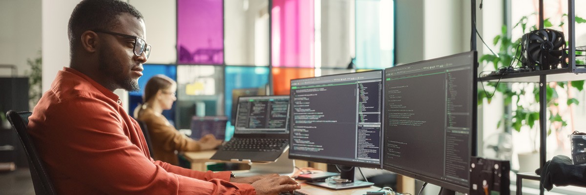 Pay Your Developers to Write Code, Not Manage It Male user working in open office writing code