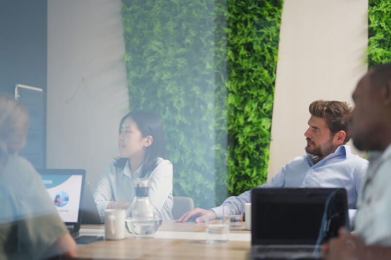 Learn how to redefine your IT maintenance strategy to improve operations and lower costs Business professionals gathered in meeting room on devices