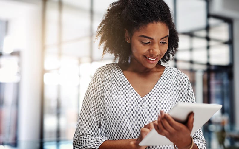 Get the facts about SD-WAN Smiling woman on tablet in bright open office