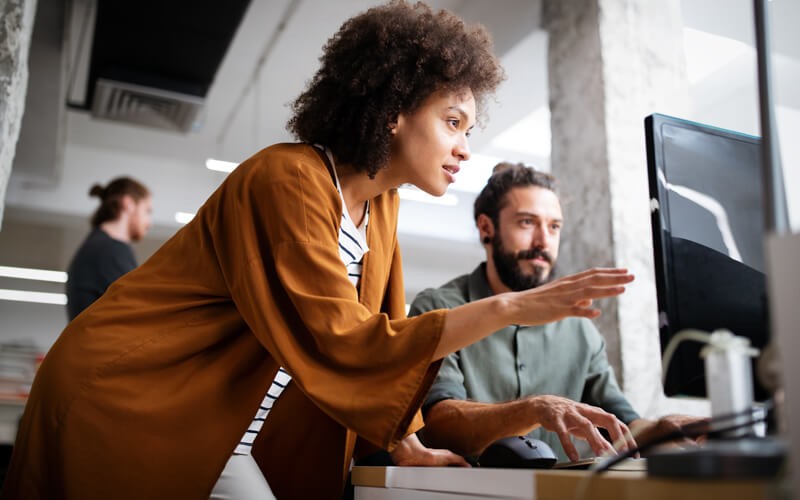 Read case studies about how organizations have benefitted Two colleagues reading case studies on desktop computer