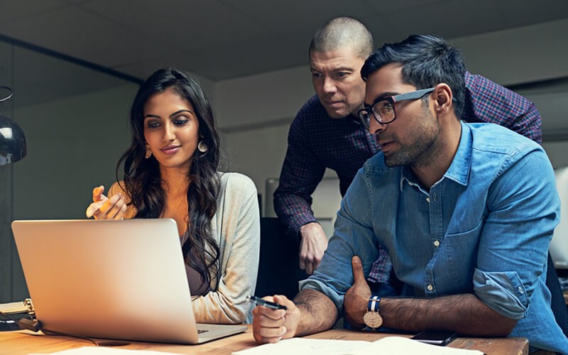 Explore the financial and productivity gains Group of business professionals discussing report on computer