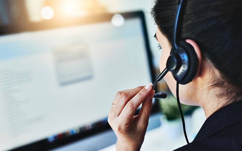 Take a deep dive into current challenges facing contact centers Woman on headset device using laptop computer