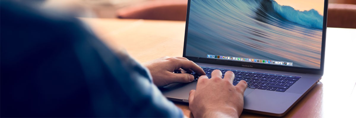 College Campus Fast Tracks Deployment for Distance Learning Close up of man using Apple laptop device