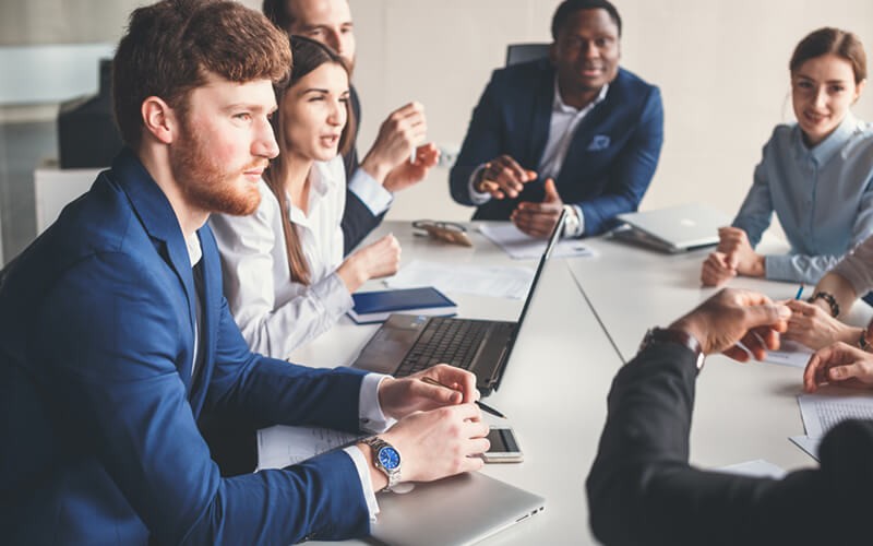 We envision, build and deliver innovative solutions Group of business professionals gathered in meeting to discuss strategy