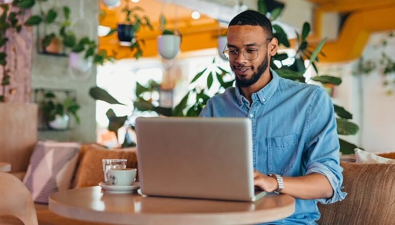 Equifax embraces secure generative AI with Gemini guy smiling on laptop
