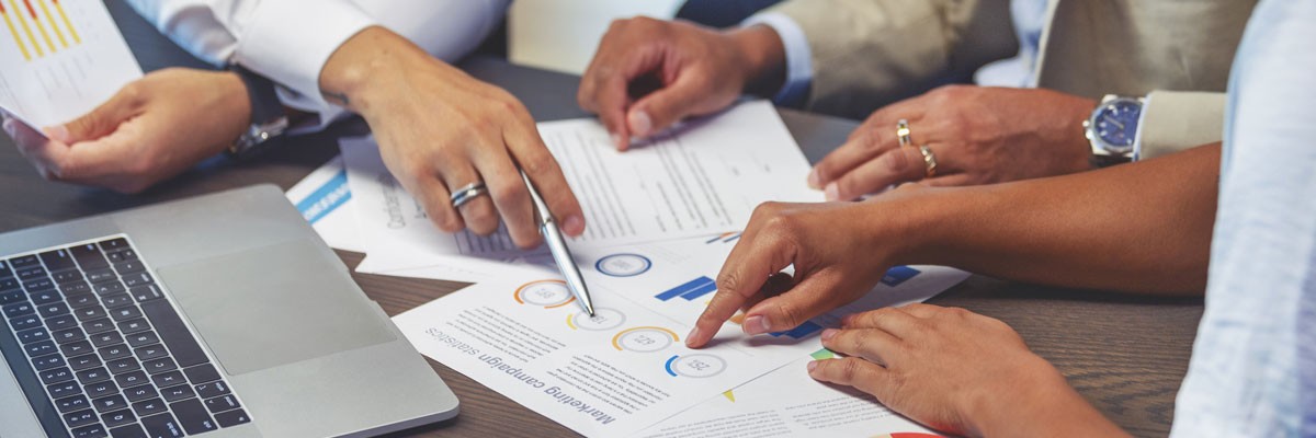 Financial Services Provider with 30+ Locations Implements High Performance, Cost-Effective DR/Backup Solution Group of financial analysts gathering around to review data