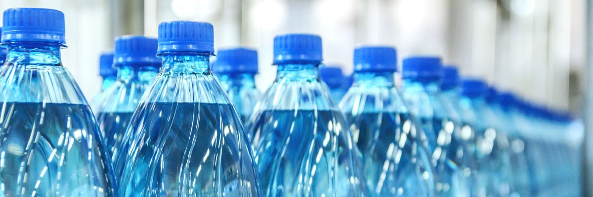 Large U.S. Beverage Bottler Implements Advanced Wired and Wireless Networks Close up of water bottle manufacturing on conveyor belt