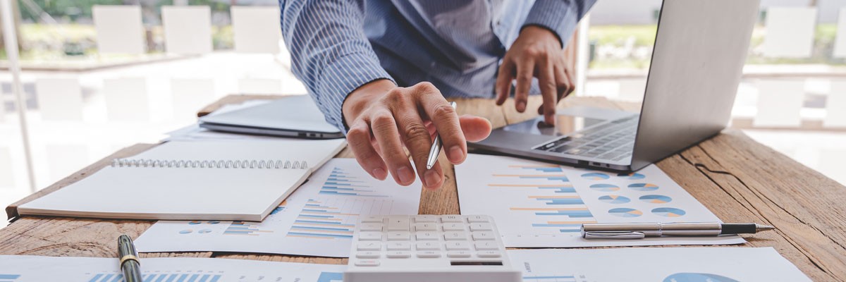 Mid-Size Financial Institution Upgrades Their Cloud Architecture with a More Efficient and Cost-Effective Solution Financial analyst reviewing data with laptop computer while using calculator