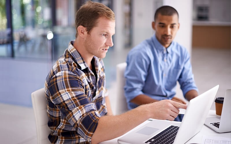 We understand the tension between simultaneously running and innovating your business Business professionals review data on laptop computer