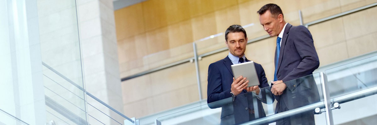 Tech Company Realizes Global-Scale Performance Gains With Evergreen Storage Two businessmen look at tablet device in open office space