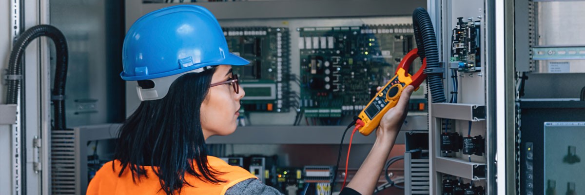 Testing and Electronics Firm Enables Growth and Innovation Woman in hard hat tests electronic devices in networking room