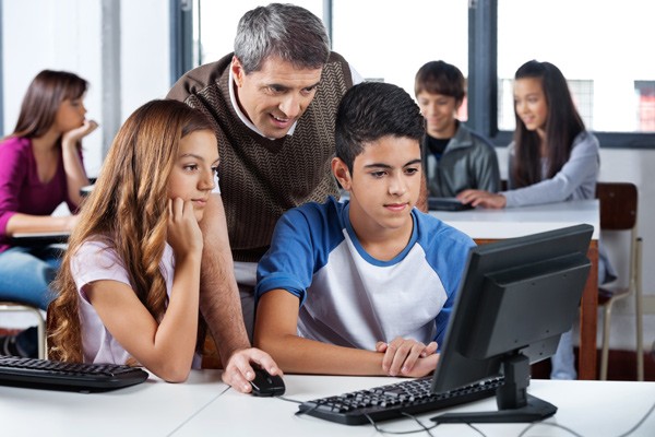 Cybersecurity in schools Teaching helping young studenst working on laptop.