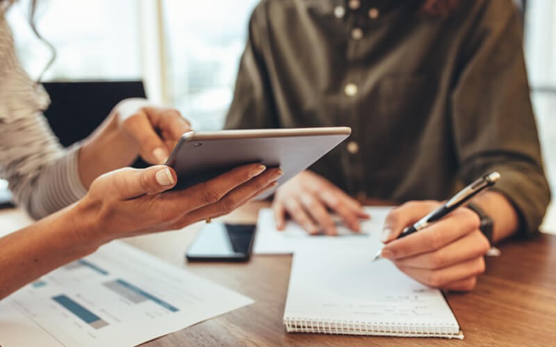 Discover how digital signage and displays help retailers Two business people reading results on tablet device