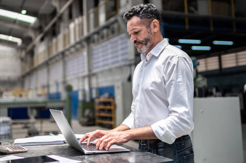 small-businessman-using-laptop-in-modern-factory small-businessman-using-laptop-in-modern-factory