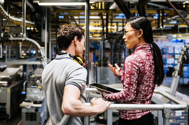 Emerging Tech Trends for a More Resilient Factory Two employees in factory with technology