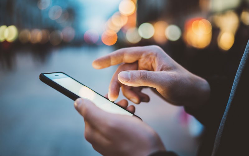 End-to-End Mobile Device Management Close up of hand touching mobile phone screen