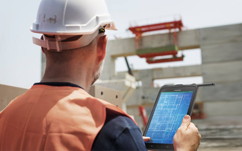 The most common challenges facing growing businesses Construction worker on tablet device looking at site