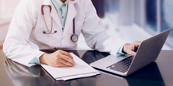 Review several benefits of SD-WAN for healthcare providers. Doctor reviewing patient info securely over SD-WAN network.