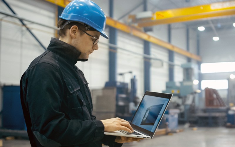 Revolutionize all areas of the factory floor Man in hardhat on laptop in factory