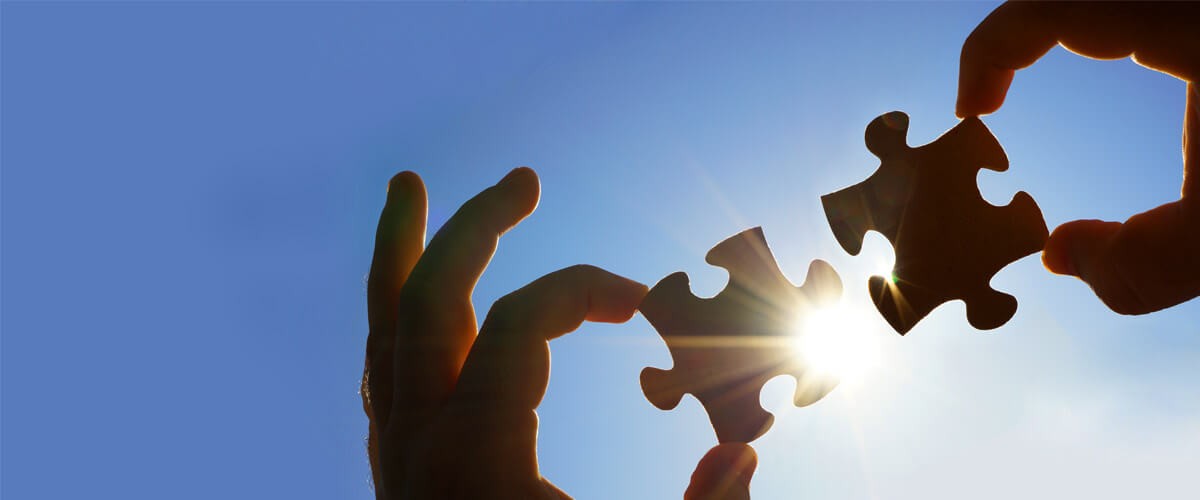 Hybrid IT partnerships: critical to business continuity two puzzle pieces being held up to the sun