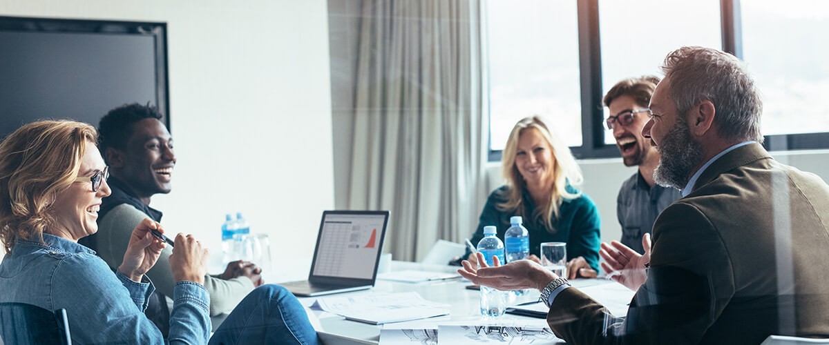 Technology Ahead Business people in a meeting all smiling attentively at the man speaking
