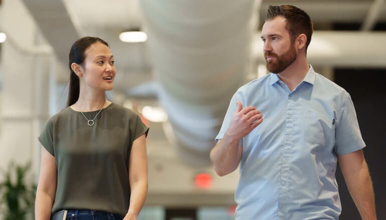 Mentorship experiences can be mutually beneficial to mentors and mentees Mentor walking and talking in modern office with mentee