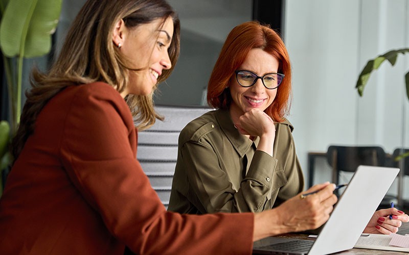 Organizations can take command of their security and compliance. Two woman collaborating