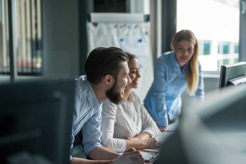 Enhanced File Transfer SMB Young team of 3 office workers looking at monitor enthusiasticallly.