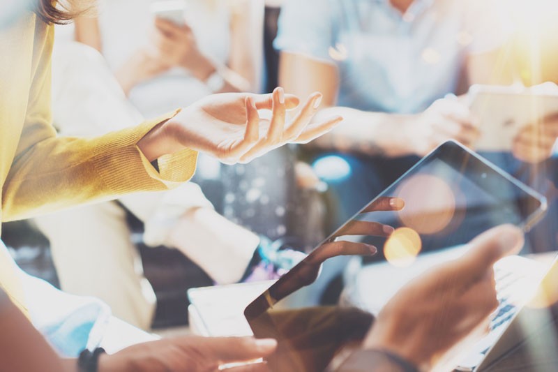 AEnhanced File Transfer Cloud Services Closeup of a group of office workers having a meeting using tablets.