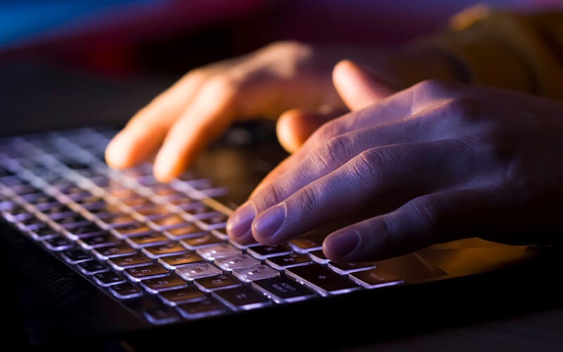 Threat Command by Rapid7 Person typing on laptop