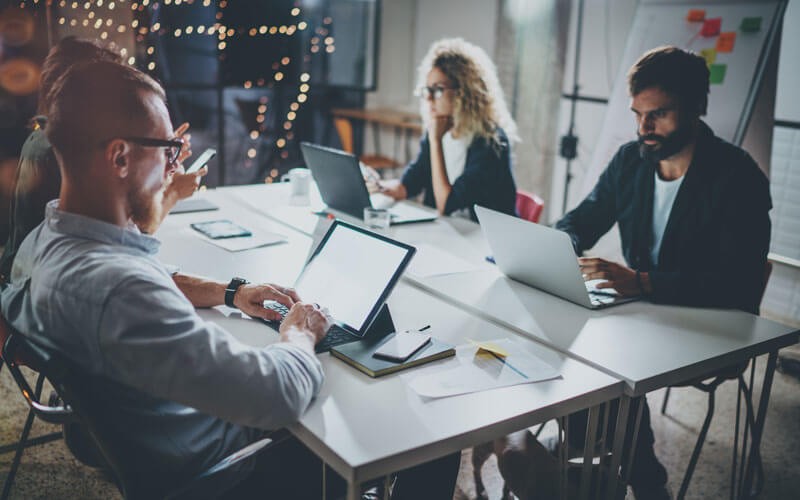 Fast startup times to maximize efficiency Group of colleagues working late on devices in office at night