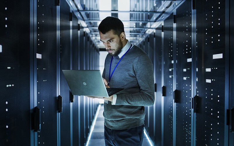 Store everything with cloud tiering. Person using a laptop inside of data center