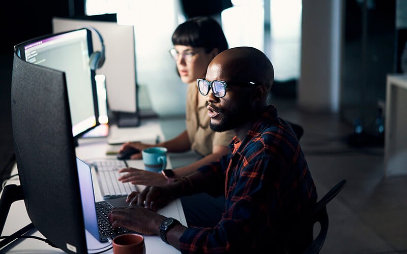 Insight will help you lead your business confidently with data Two developers work on desktop computers in office at night