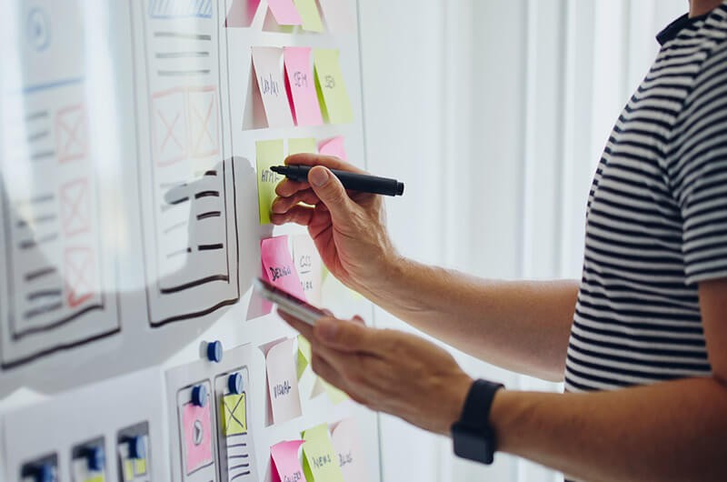 Design strategy consulting bridges the gap between expectation and reality to produce an effective product. UX Designer working with client during design strategy session