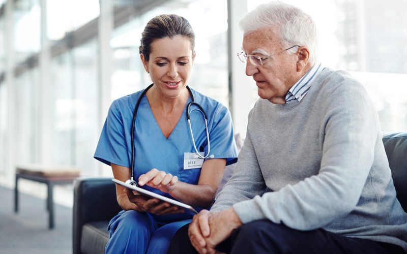 Patient information is the backbone of your healthcare organization Nurse with tablet explains treatment options to elderly patient