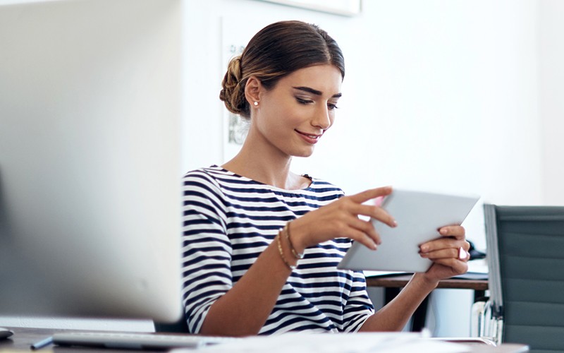 Dynamic technology solutions. Smiling businesswoman on tablet device near computer enjoying seamless data integration